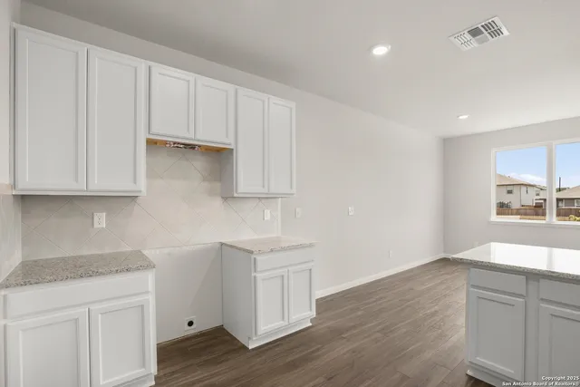 a kitchen with granite countertop white cabinets and a sink