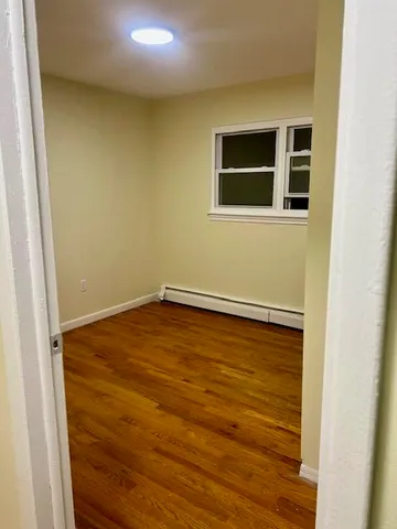 a view of a big room with wooden floor and a window