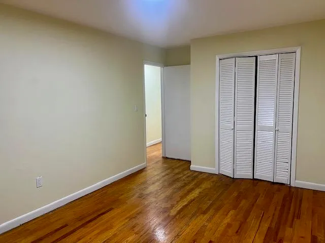 an empty room with wooden floor and closet