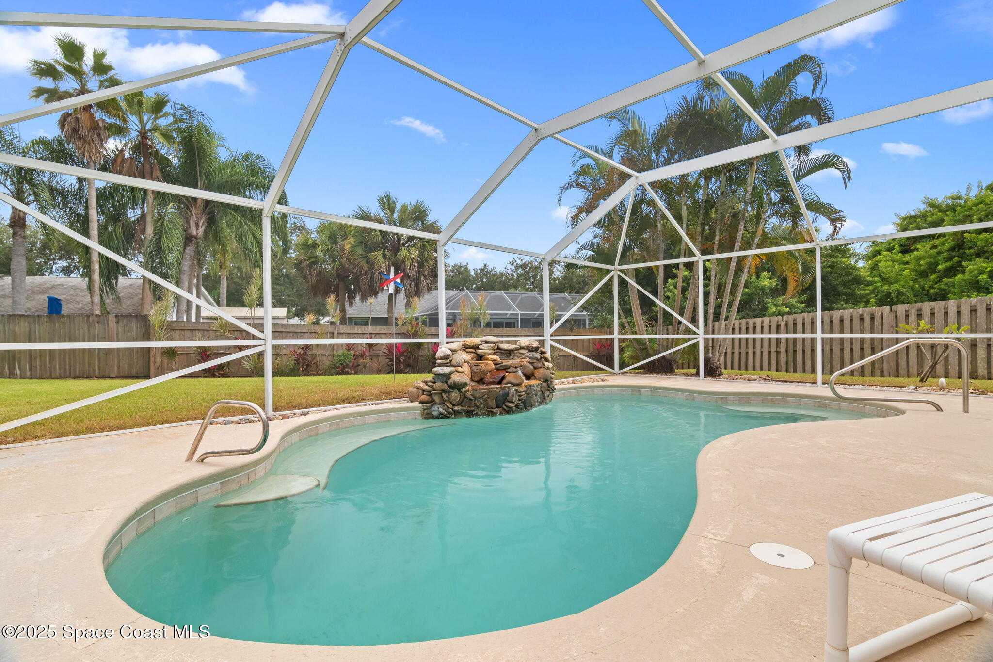 4664 Grand Meadows Boulevard Melbourne, FL 32934 - Photo 25 of 32 a view of a swimming pool with a garden and trees in the background