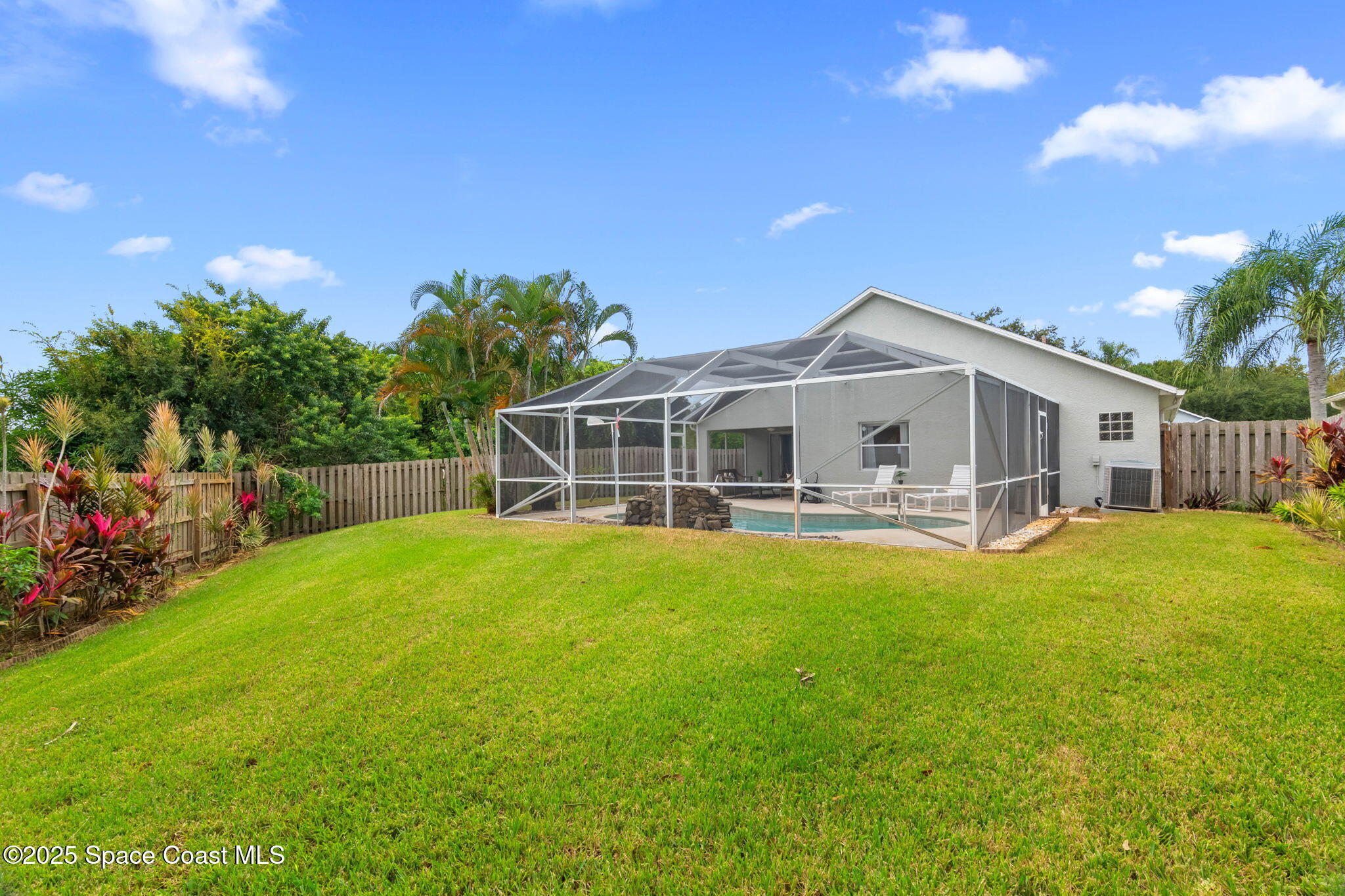 4664 Grand Meadows Boulevard Melbourne, FL 32934 - Photo 26 of 32 a view of a white house with a big yard and potted plants