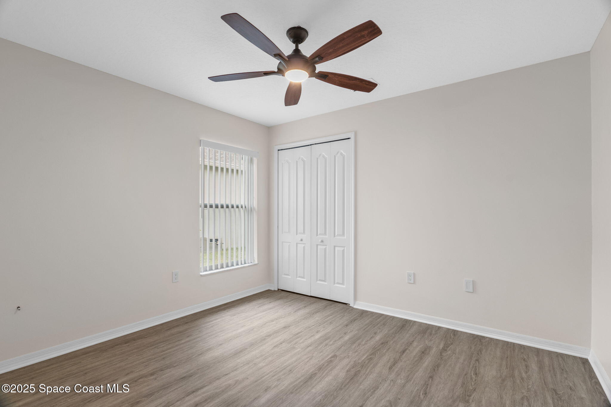 4664 Grand Meadows Boulevard Melbourne, FL 32934 - Photo 6 of 32 an empty room with wooden floor and ceiling fan