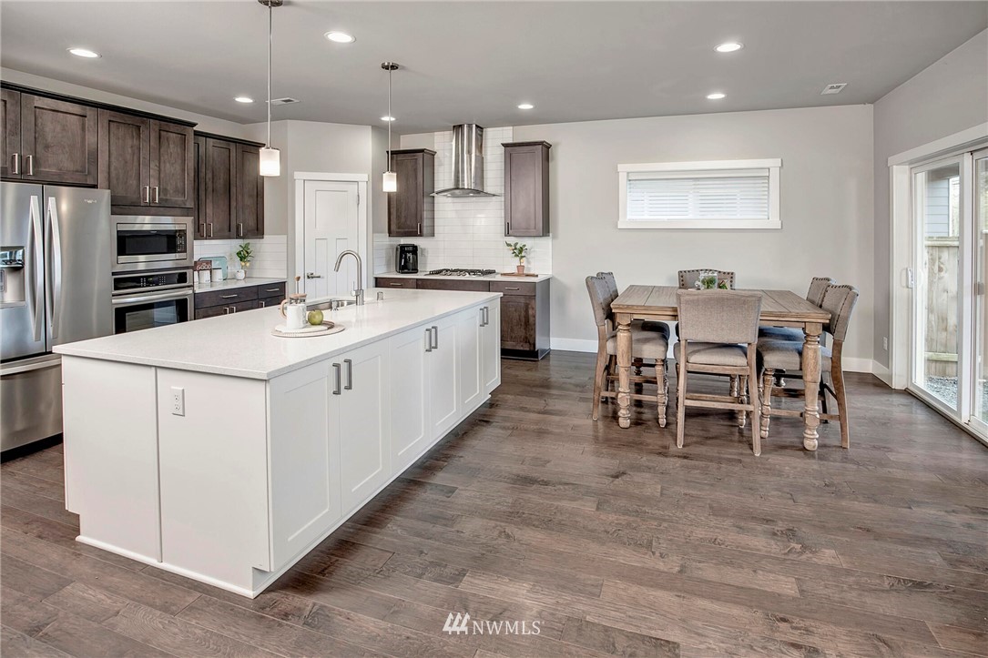 20403 South Danvers Road, Unit B Lynnwood, WA 98036 - Photo 12 of 29 a kitchen with stainless steel appliances kitchen island granite countertop a stove a sink a dining table and chairs