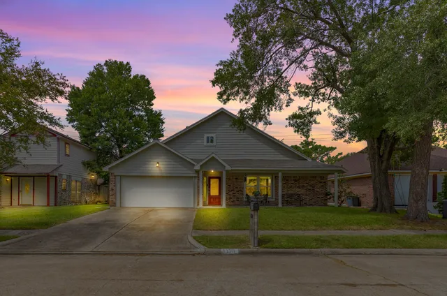 a front view of a house with a garden and trees
