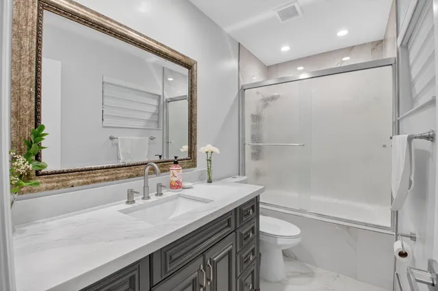 a bathroom with a granite countertop sink a toilet and shower