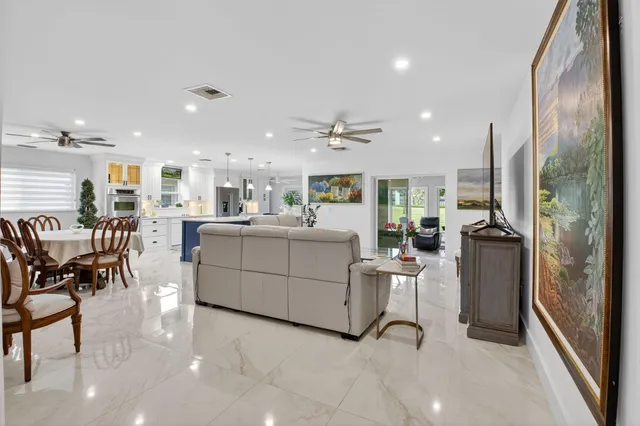 a view of a kitchen with kitchen island stainless steel appliances refrigerator stove dining table and chairs