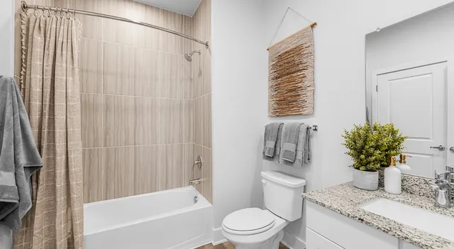 a bathroom with a granite countertop sink a toilet and shower