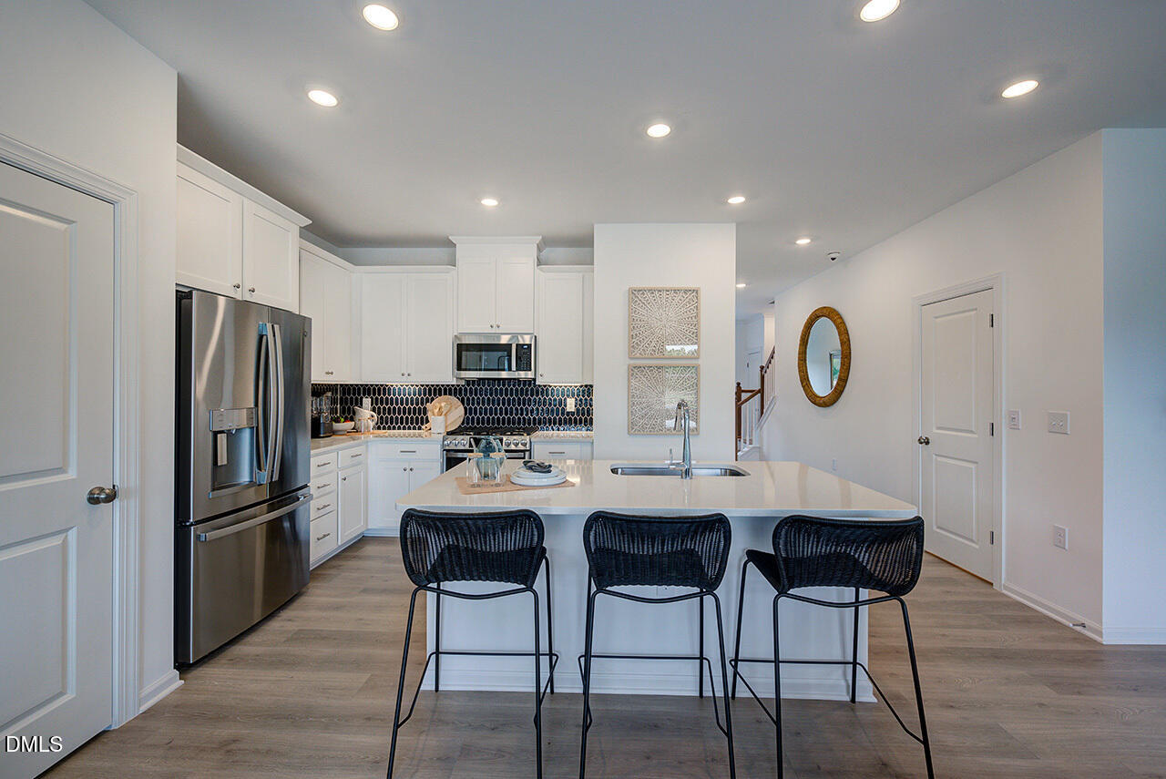 51 Shay Street Angier, NC 27501 - Photo 11 of 41 a kitchen with stainless steel appliances kitchen island granite countertop a refrigerator a stove a sink and a dining table with chairs