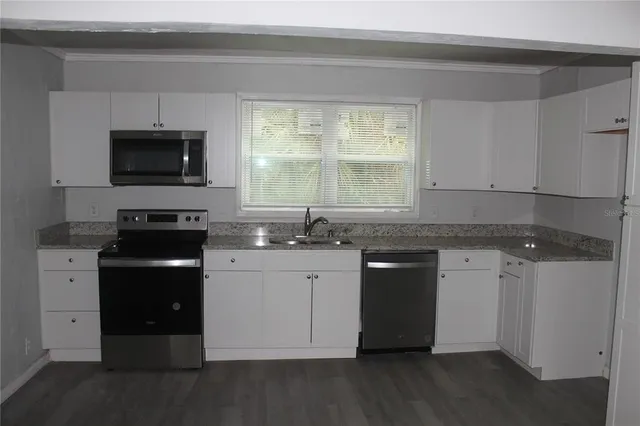 a kitchen with granite countertop a stove a sink and a microwave
