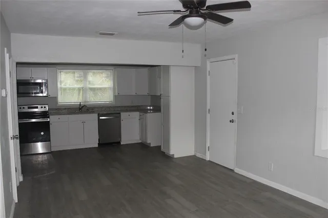 a kitchen with stainless steel appliances a sink a stove a refrigerator cabinets and a window