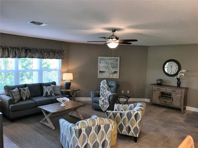 a living room with furniture a chandelier fan and a large window