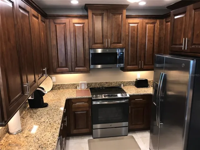 a kitchen with granite countertop wooden cabinets and a stove top oven