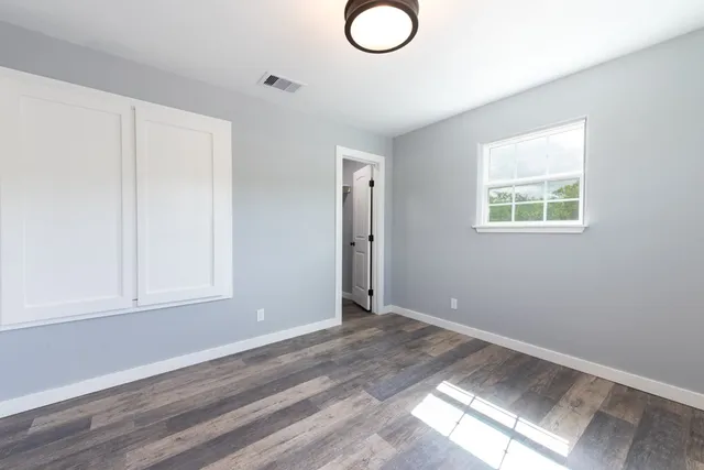 an empty room with wooden floor and windows