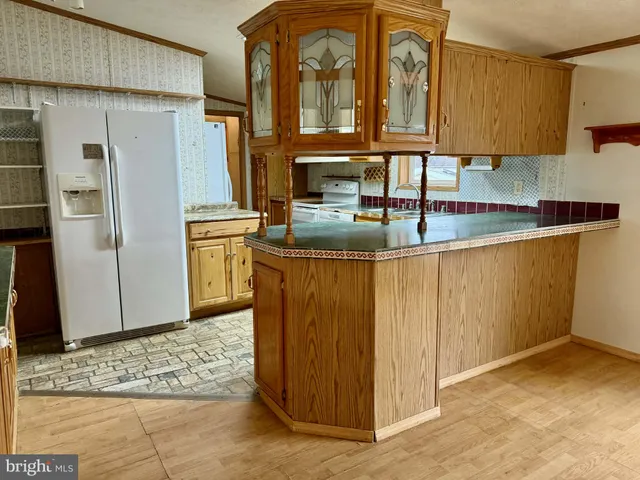 a kitchen with stainless steel appliances granite countertop a refrigerator a stove and a sink with wooden cabinets