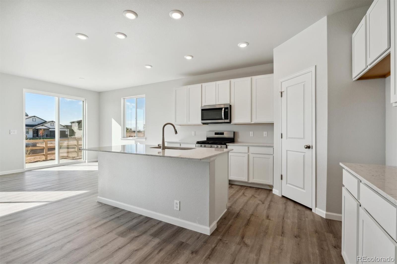 4264 Gozzer Ranch Drive Elizabeth, CO 80107 - Photo 4 of 21 a kitchen with white cabinets and wooden floor
