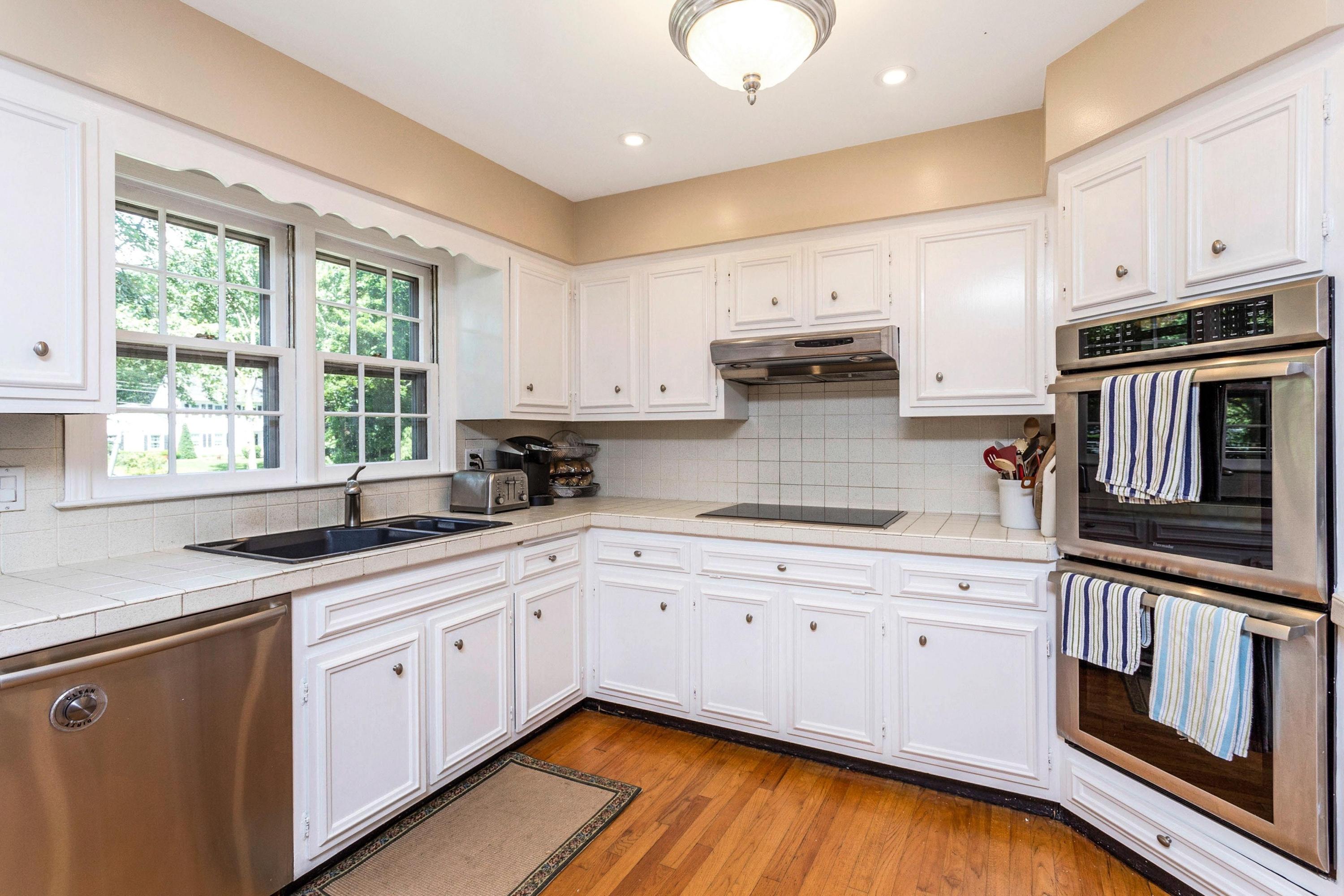 34 Country Club Road Darien, CT 06820 - Photo 7 of 17 a kitchen with stainless steel appliances granite countertop a stove a sink dishwasher and white cabinets with wooden floor