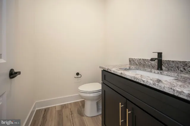 a bathroom with a granite countertop sink a toilet and a mirror
