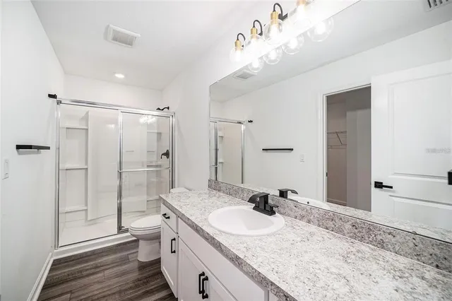 a bathroom with a granite countertop sink a toilet and shower