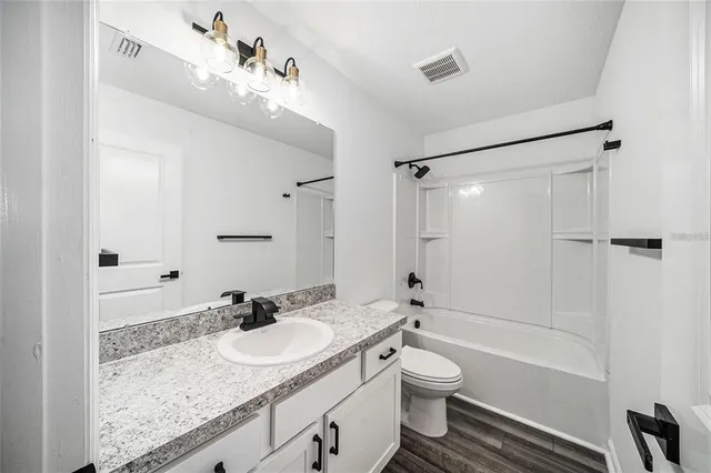 a bathroom with a granite countertop sink toilet a shower and a mirror