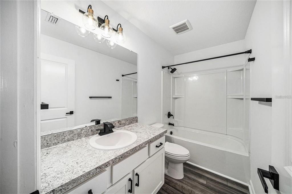 35542 Buttonweed Trail Zephyrhills, FL 33541 - Photo 22 of 30 a bathroom with a granite countertop sink toilet a shower and a mirror