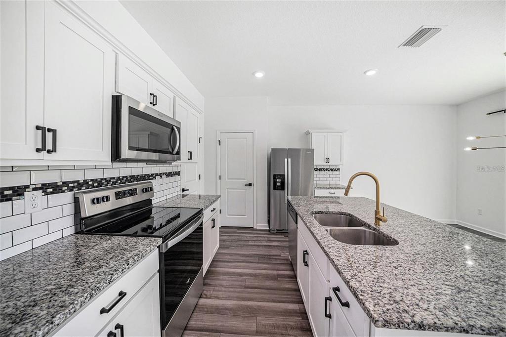 35542 Buttonweed Trail Zephyrhills, FL 33541 - Photo 3 of 30 a kitchen with stainless steel appliances kitchen island granite countertop a sink and a refrigerator