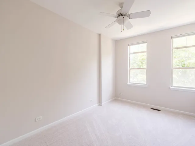 an empty room with a window and a fan