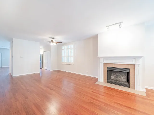 a view of an empty room with wooden floor fireplace and a window