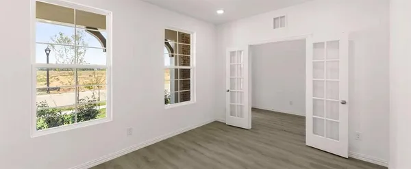 an empty room with wooden floor and windows