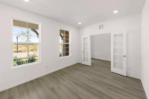 an empty room with wooden floor and windows