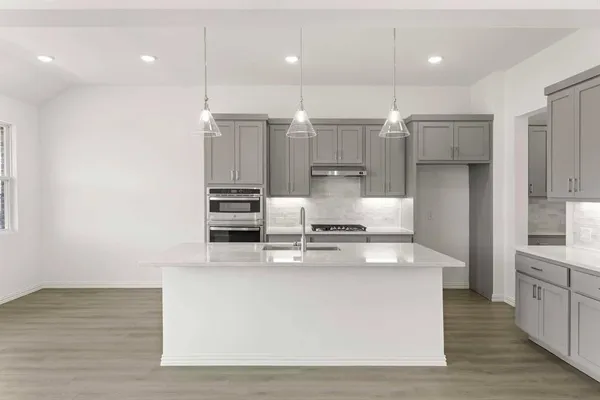 a large kitchen with stainless steel appliances a large counter top and wooden floors