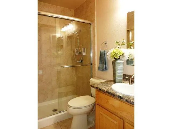 a bathroom with a granite countertop sink a toilet and shower