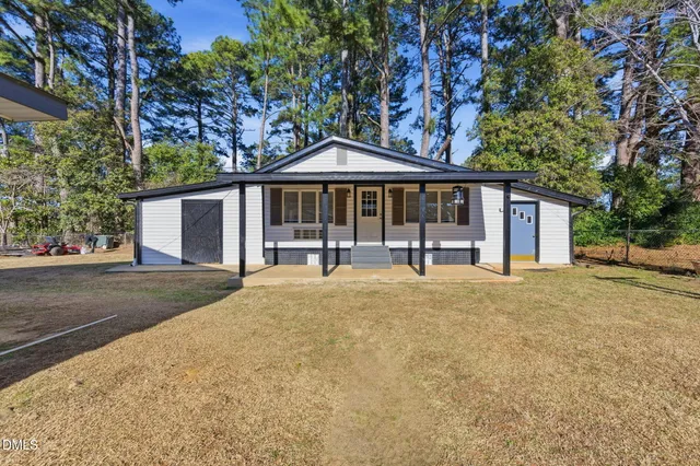 a backyard of a house with plants and large tree