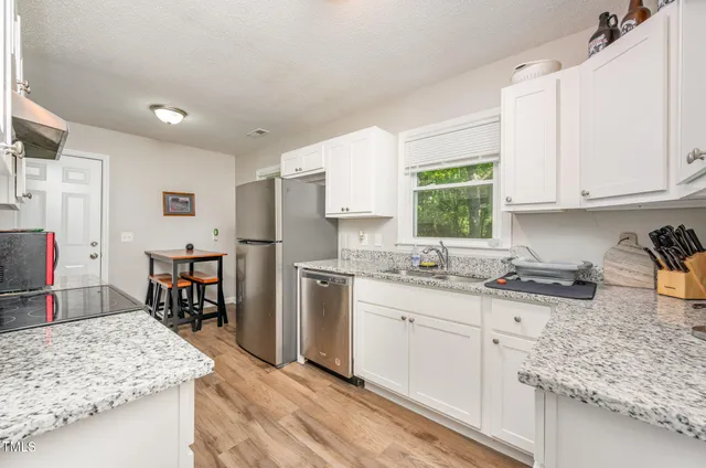 a kitchen with granite countertop a sink stove and cabinets