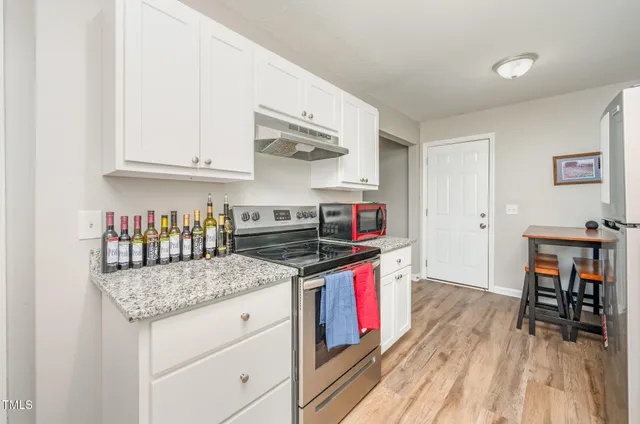 a kitchen with stainless steel appliances granite countertop a stove and a wooden floors