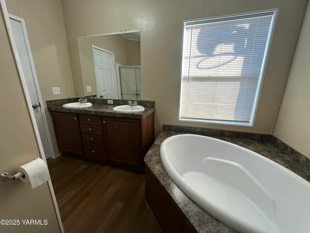 a spacious bathroom with a granite countertop sink a mirror and a bathtub