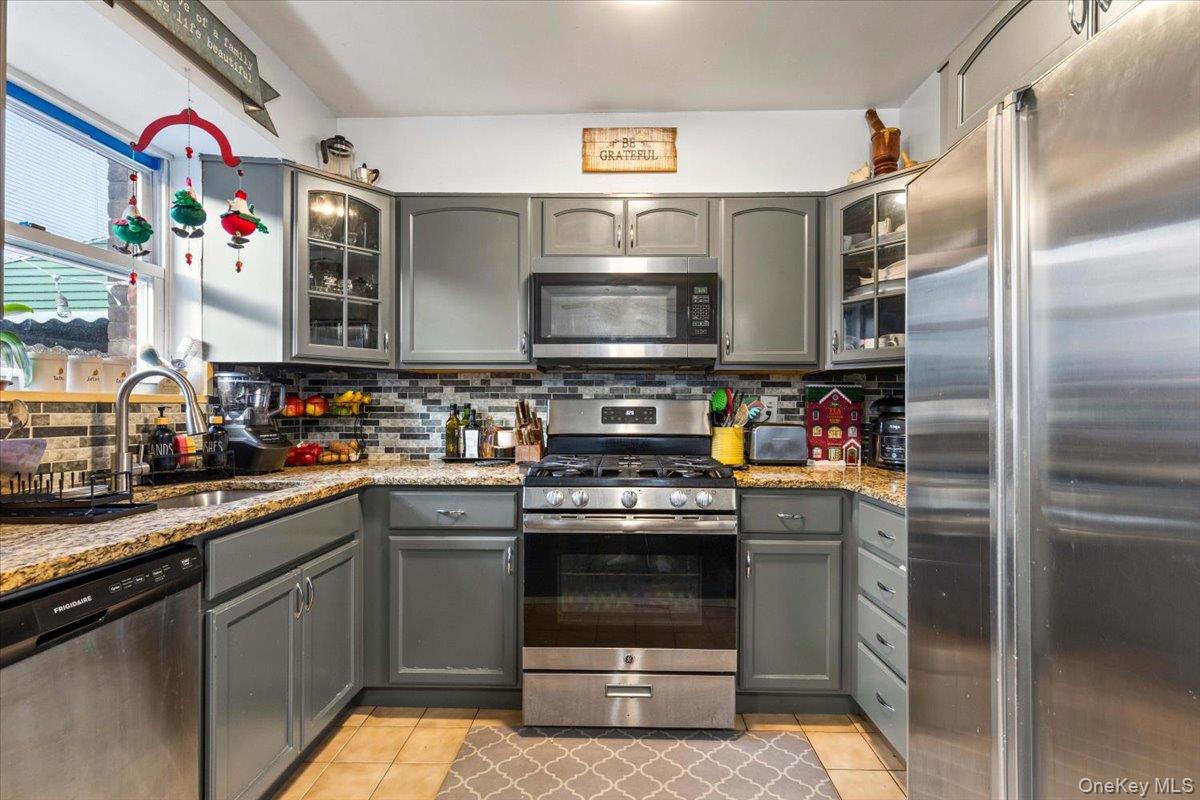 2761 Hering Avenue Bronx, NY 10469 - Photo 12 of 29 Kitchen with gray cabinetry, appliances with stainless steel finishes, and glass insert cabinets