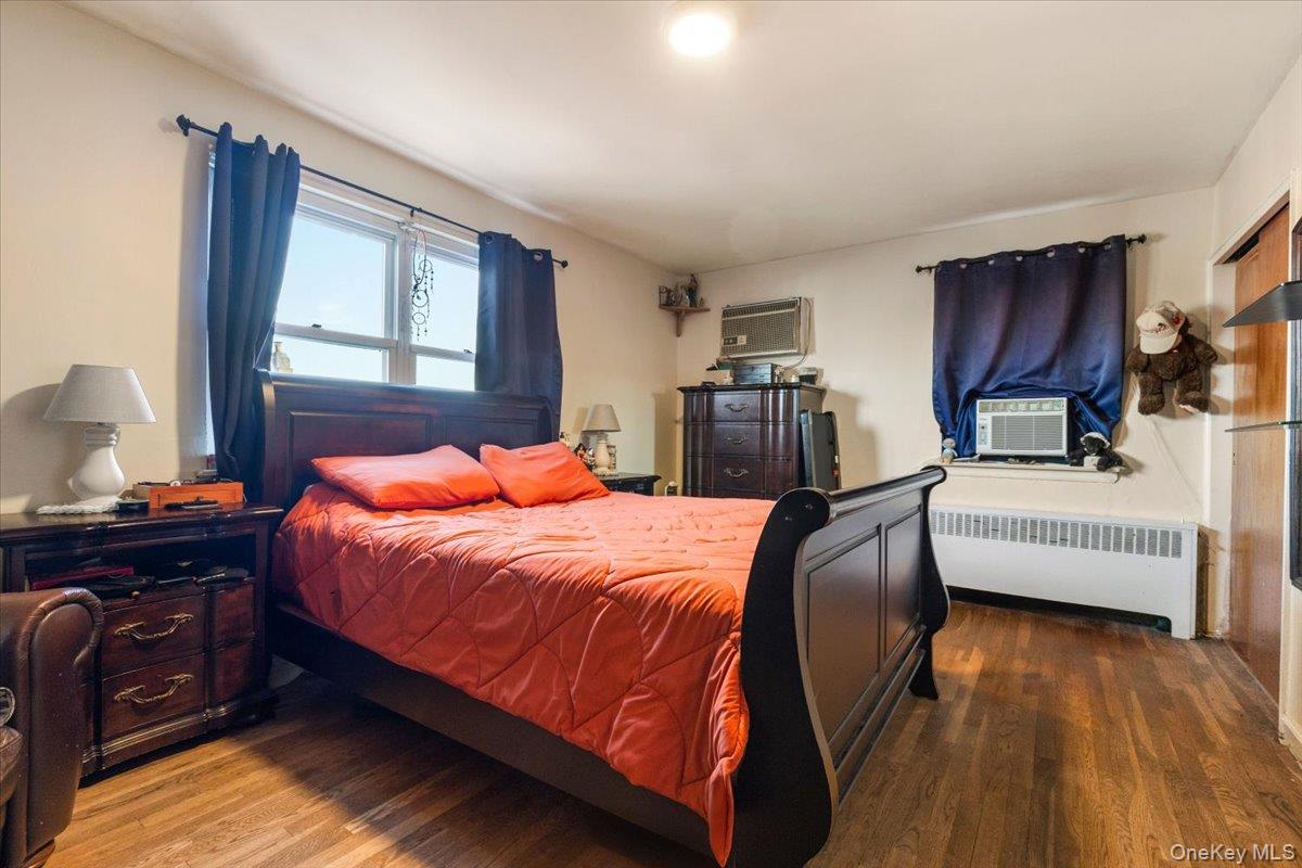 2761 Hering Avenue Bronx, NY 10469 - Photo 15 of 29 Bedroom featuring radiator heating unit, wood finished floors, cooling unit, and a wall unit AC