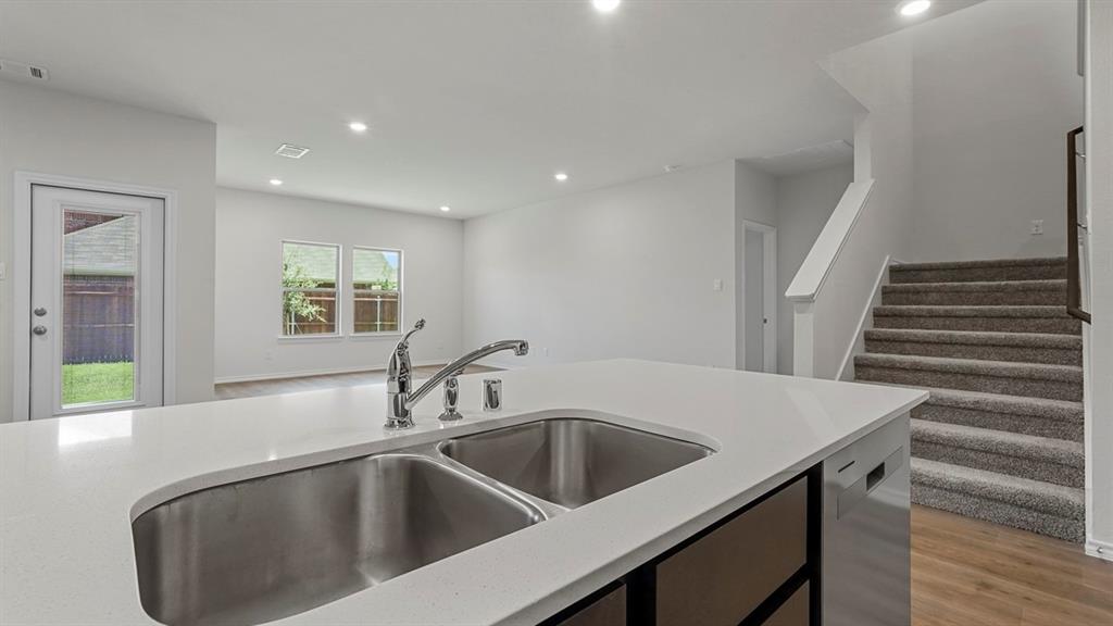 1627 Mantle Road Crandall, TX 75114 - Photo 8 of 40 Kitchen island with dual stainless steel sink and chrome faucet, recessed lighting, wood-finish flooring, and carpeted staircase