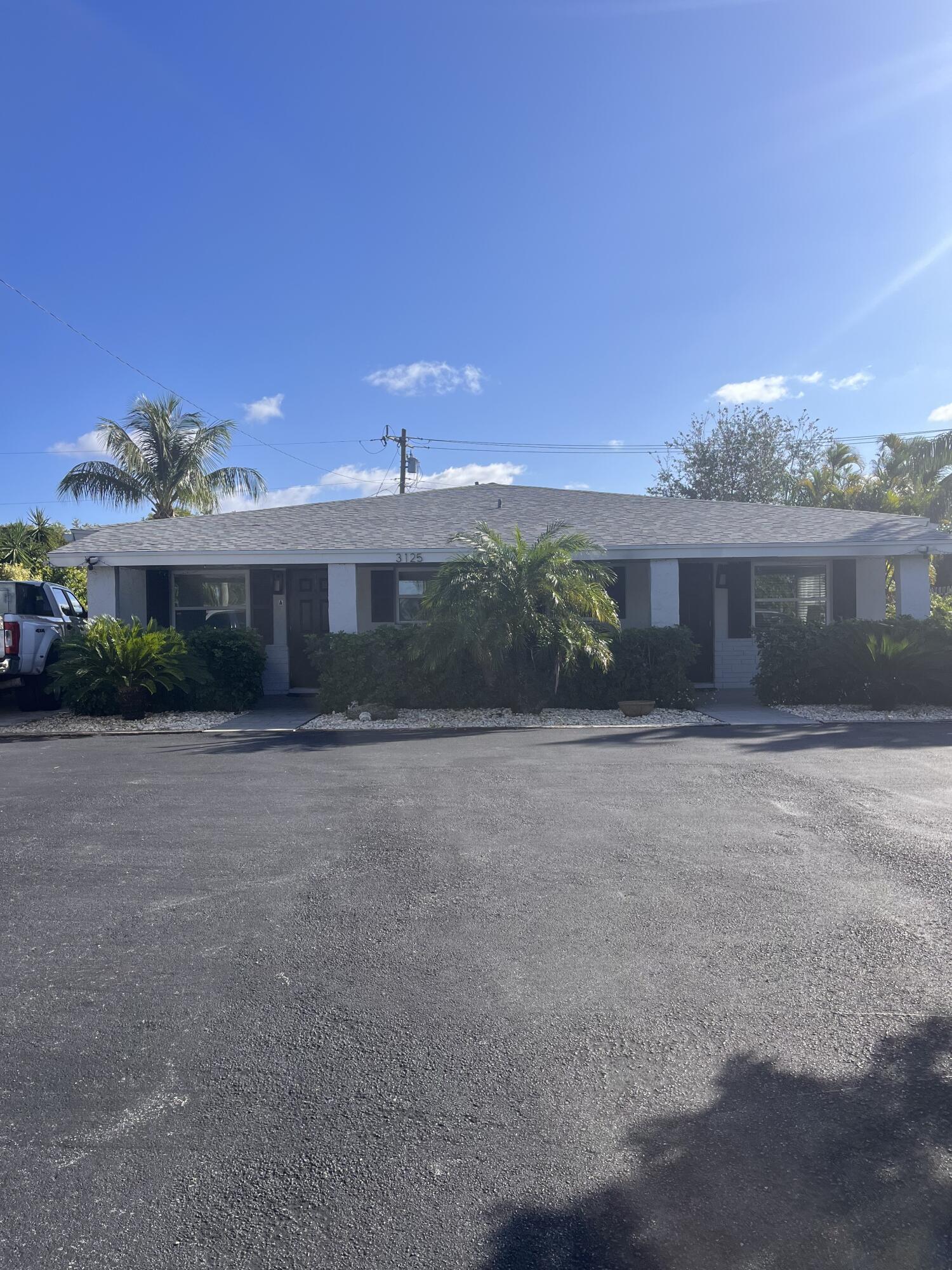 3125 Albatross Road, Unit B Delray Beach, FL 33444 - Photo 1 of 16 a front view of a house with a yard and a garage