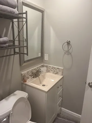 a bathroom with a sink and mirror with toilet