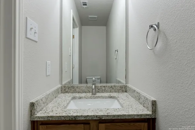 a bathroom with a granite countertop sink and a mirror