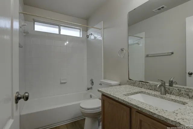 a bathroom with a granite countertop sink toilet and shower