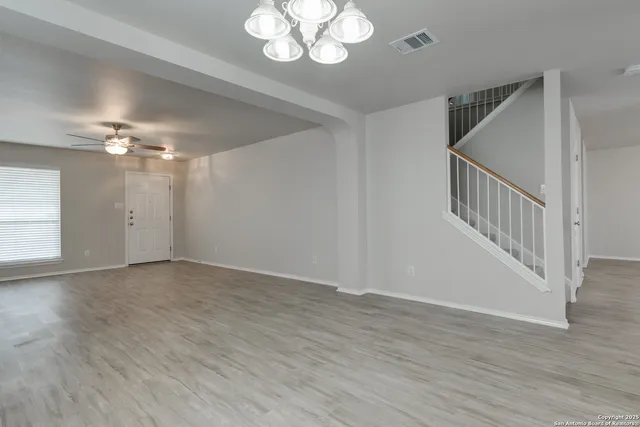 a view of an empty room with wooden floor and staircase