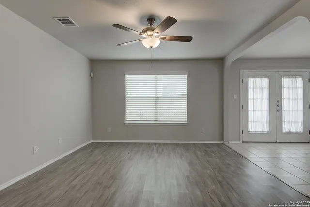 an empty room with wooden floor and windows