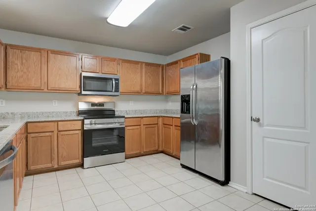 a kitchen with stainless steel appliances granite countertop a refrigerator and a stove top oven