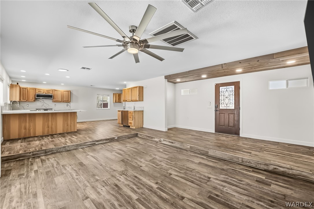 4088 Mercer Road Bullhead City, AZ 86429 - Photo 8 of 35 Spacious open-concept living area featuring wood-finish flooring, a large ceiling fan, recessed lighting, and a kitchen with light wood cabinetry and light countertops