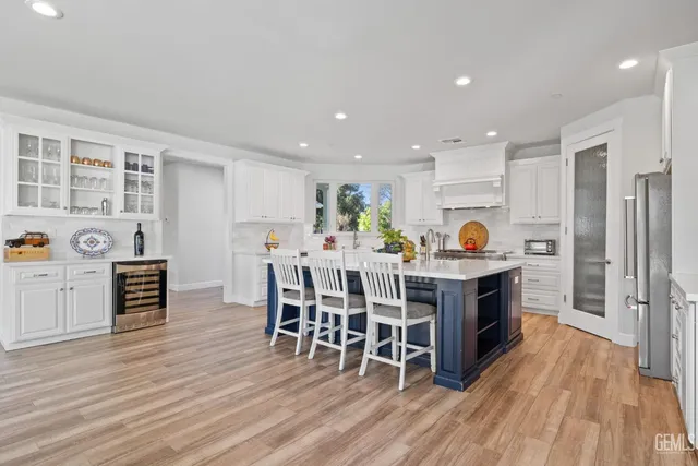 a kitchen with stainless steel appliances granite countertop a refrigerator a microwave a stove and white cabinets with wooden floor