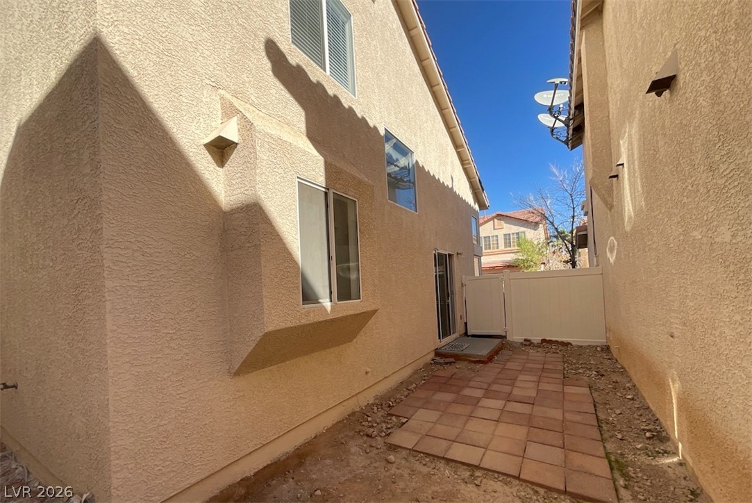7203 Cestrum Road Las Vegas, NV 89113 - Photo 21 of 22 Tiled patio space sits nestled between stucco home exteriors under clear blue skies.