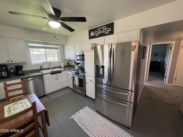 a kitchen with stainless steel appliances granite countertop a refrigerator a sink a stove and white cabinets