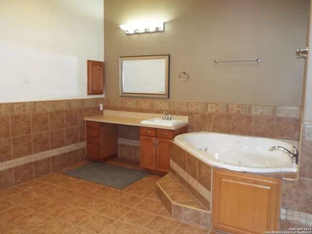 a bathroom with a tub a sink and mirror